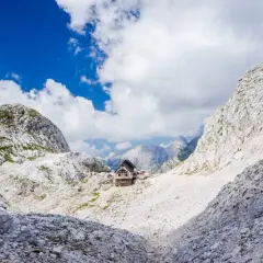 Hütte in den Julischen Alpen, idealer Rastplatz für eine Triglav Wanderung. Majestätische Berglandschaft unter blauem Himmel.