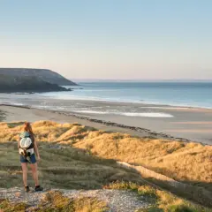 Zwei Wanderer mit Rucksäcken genießen den Ausblick auf die Küste der Bretagne.