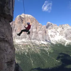 Abseilen in den Dolomiten: Ein Kletterer seilt sich vor majestätischer Bergkulisse ab.