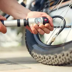 Person pumpt Fahrradreifen auf. Der Reifendruck vorne und hinten ist wichtig für die Fahrt.