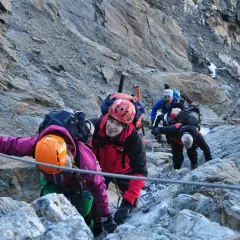 Bergsteiger seilen sich auf dem Weg zur Wildspitze ab. Ein Mann im roten Anzug lächelt in die Kamera.