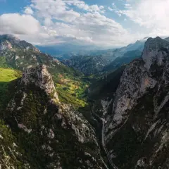 Majestätische Berge der Picos de Europa, grüne Täler und eine Straße, die sich durch die Schlucht schlängelt.