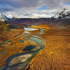 Herbstliche Landschaft mit Flüssen und Seen, ideal für fernwanderwege schweden. Schneebedeckte Berge im Hintergrund.