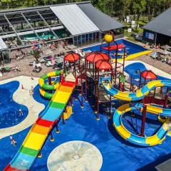 Bunter Wasserrutschen-Spaß auf einem Campingplatz mit Pool im Allgäu. Kinder planschen und rutschen ausgelassen.