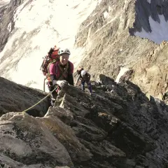 Zwei Bergsteiger klettern gesichert über den Normalweg am Lagginhorn. Die felsige Route führt durch steiles Gelände mit Schneefeldern im Hintergrund.