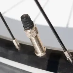 Nahaufnahme eines Fahrradreifens mit einem Presta-Ventil. Dieses Ventil ist schmal und hat eine kleine Mutter an der Spitze, die man zum Aufpumpen aufschrauben muss.