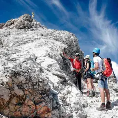 Bergsteiger erklären den Weg zur Zugspitze ohne Klettersteig. Ein Führer zeigt auf den Gipfel.