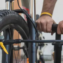 Hände pumpen einen Reifen auf. Der richtige Reifendruck für ein Fahrrad mit 20 Zoll Rädern ist wichtig für die Fahrt.