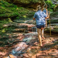 Zwei Kinder erkunden einen moosbewachsenen Bachlauf im Schwarzwald. Ein echter Geheimtipp zum Wandern!