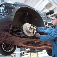 Mechaniker arbeitet am quietschenden Vorderrad eines Autos.