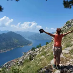 Frau genießt die Aussicht beim **Montenegro wandern**. Der Blick schweift über die Bucht von Kotor, umgeben von Bergen.