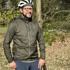Mann mit Fahrradhelm und Patagonia Regenjacke im Wald. Die Jacke ist leicht und ideal für Outdoor-Abenteuer.