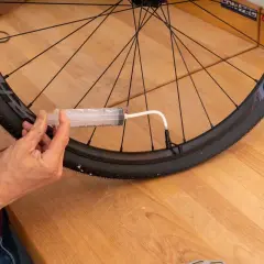 Mit einer Spritze wird Dichtmilch in den Fahrradreifen gefüllt, um die Laufrichtung zu optimieren und Pannen zu vermeiden.