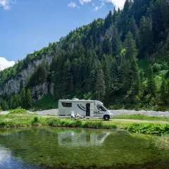 Wohnmobil am Bergsee. Hier darf man in der Schweiz wild campen, umgeben von grünen Hängen und Nadelbäumen.
