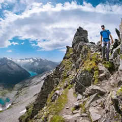 Wanderer auf einem steinigen Pfad der Peter Habeler Runde mit Blick auf türkisfarbene Bergseen und schneebedeckte Gipfel.