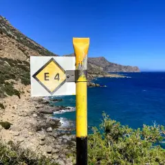 Wegweiser E4 auf Kreta, mit Blick auf das tiefblaue Meer und die felsige Küste.