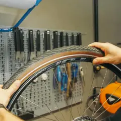 Mann wechselt den Fahrradschlauch. Werkzeugwand im Hintergrund.