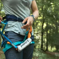 Person legt Klettersteigset an. Sicherungsgurt mit Karabiner und Seil im Wald.