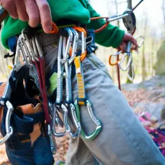 Kletterer mit Ausrüstung für trad klettern, Kletterschuhe hängen am Gurt.