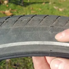 Finger zeigt auf abgefahrenen Fahrradreifen mit der Aufschrift "ROTATION". Zeit, wann Fahrradreifen wechseln.