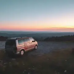 Ein Campervan steht auf einem Hügel bei Sonnenuntergang. Die Frage "was kostet wildcampen" stellt sich hier nicht, denn die Aussicht ist unbezahlbar.