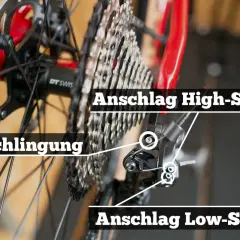 Detailaufnahme des Schaltwerks eines Fahrrads. Hier wird gezeigt, wie man die Shimano Schaltung einstellen kann, mit Markierungen für Anschlag High-Speed, Anschlag Low-Speed und Umschlingung.