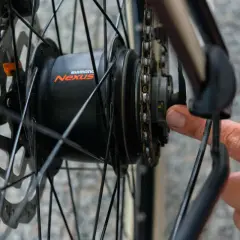 Hand stellt die Shimano Nabenschaltung ein. Ein kleiner gelber Strich ist sichtbar.