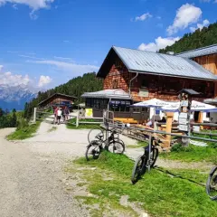 Bergpanorama in den Tuxer Alpen mit Holzhütte, Fahrrädern und E-Bike-Tankstelle.
