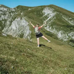 Glückliche Wanderin mit erhobenen Armen und Stöcken genießt die Aussicht auf die Berge beim Wandern in Polen.