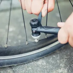 Hände pumpen mit einer kleinen Pumpe ein Fahrrad auf. Ein Reifen wird an einer Tankstelle fahrrad aufpumpen.