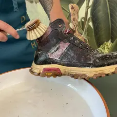 Schmutzige Wanderschuhe reinigen mit einer Bürste und Seifenwasser.
