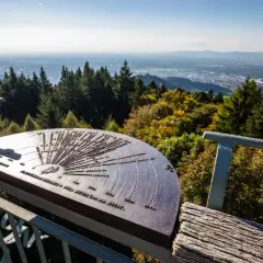 Panoramablick vom Aussichtspunkt Rosskopf Freiburg mit einer Orientierungstafel, die auf die umliegenden Berge und Täler hinweist.