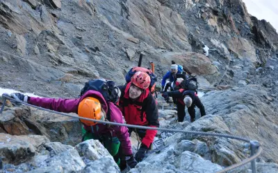 Bergsteiger seilen sich auf dem Weg zur Wildspitze ab. Ein Mann im roten Anzug lächelt in die Kamera.