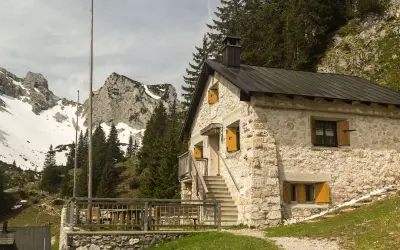 Steinernes Haus mit Holzterrasse und Bergkulisse im Tannheimer Tal. Ein Geheimtipp für Wanderer.