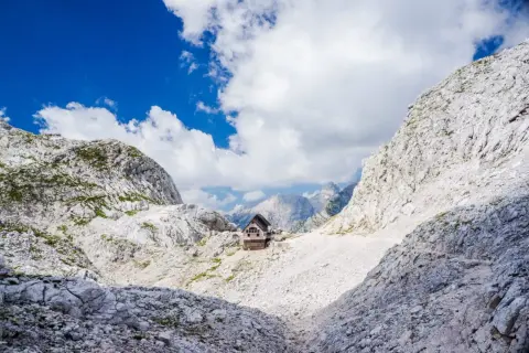 Hütte in den Julischen Alpen, idealer Rastplatz für eine Triglav Wanderung. Majestätische Berglandschaft unter blauem Himmel.