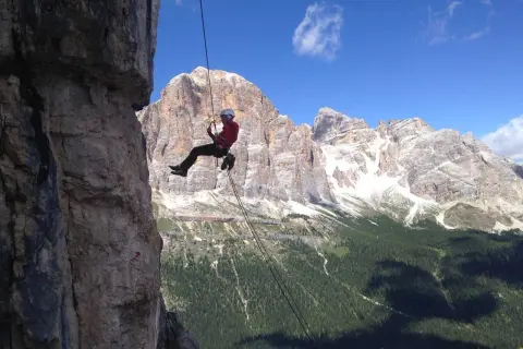 Abseilen in den Dolomiten: Ein Kletterer seilt sich vor majestätischer Bergkulisse ab.
