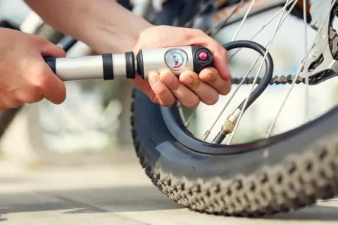 Person pumpt Fahrradreifen auf. Der Reifendruck vorne und hinten ist wichtig für die Fahrt.