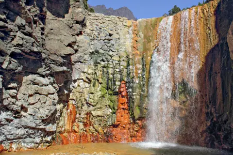 Farbenprächtiger Wasserfall mit rostfarbenen Felsen, ideal für la palma wandern. Ein Naturjuwel.