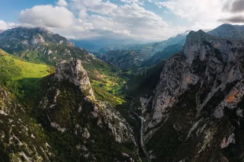 Majestätische Berge der Picos de Europa, grüne Täler und eine Straße, die sich durch die Schlucht schlängelt.