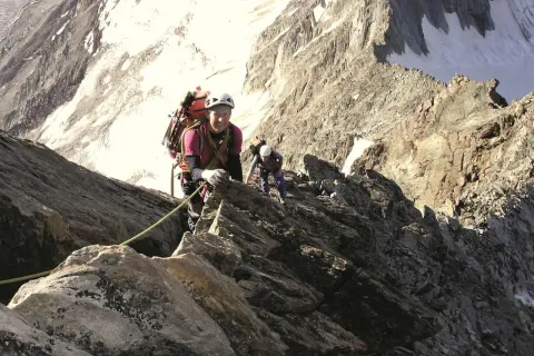Zwei Bergsteiger klettern gesichert über den Normalweg am Lagginhorn. Die felsige Route führt durch steiles Gelände mit Schneefeldern im Hintergrund.