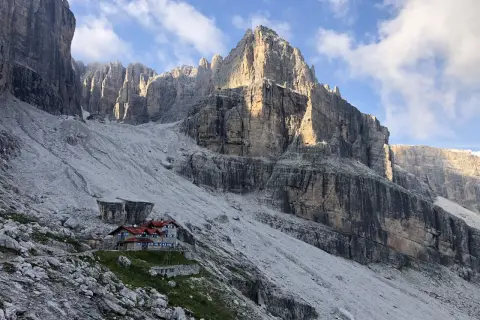 Hütte in den Brenta Dolomiten, umgeben von steilen Felswänden und Geröllfeldern. Ein majestätischer Anblick.