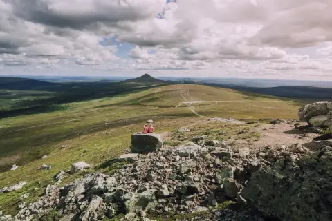 Zwei Wandererinnen genießen die weite Aussicht auf eine Berglandschaft in Schweden. Die Wolkenformationen am Himmel sind dramatisch.
