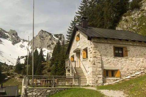 Steinernes Haus mit Holzterrasse und Bergkulisse im Tannheimer Tal. Ein Geheimtipp für Wanderer.