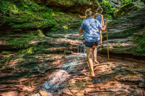 Zwei Kinder erkunden einen moosbewachsenen Bachlauf im Schwarzwald. Ein echter Geheimtipp zum Wandern!