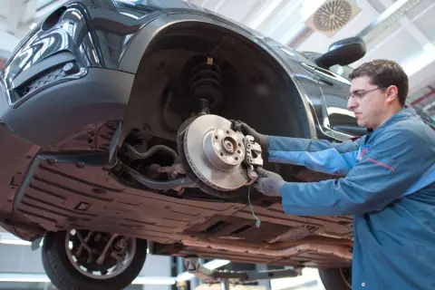Mechaniker arbeitet am quietschenden Vorderrad eines Autos.