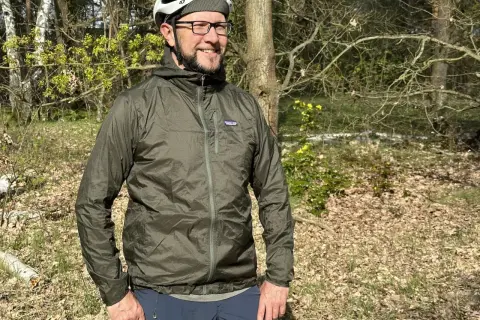 Mann mit Fahrradhelm und Patagonia Regenjacke im Wald. Die Jacke ist leicht und ideal für Outdoor-Abenteuer.
