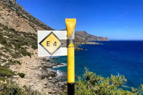Wegweiser E4 auf Kreta, mit Blick auf das tiefblaue Meer und die felsige Küste.