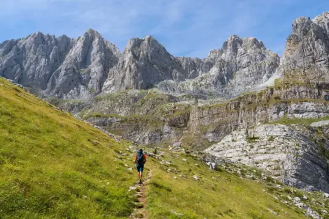 Wanderer auf einem Pfad im **high scardus trail** vor imposanten Felsformationen.