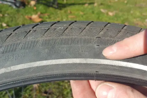 Finger zeigt auf abgefahrenen Fahrradreifen mit der Aufschrift "ROTATION". Zeit, wann Fahrradreifen wechseln.