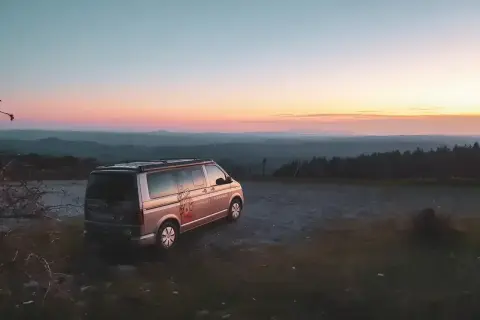 Ein Campervan steht auf einem Hügel bei Sonnenuntergang. Die Frage "was kostet wildcampen" stellt sich hier nicht, denn die Aussicht ist unbezahlbar.